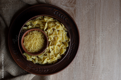 Different types of pasta lie in brown vintage plates on a wooden table and sacking top view