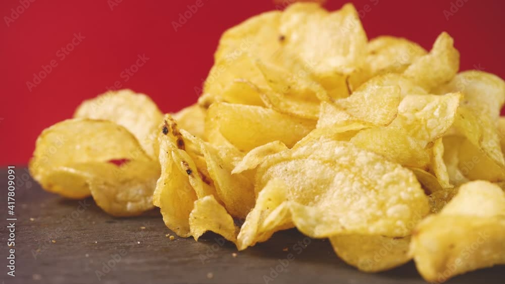 golden potato chips falling on red background. food background. Salted potatoes chips. golden fried chips on black . Fast salty food for snack or party. Tasty food for appetizer. golden potato chips falling on red background. food background. Salted potatoes chips. golden fried chips on black . Fast salty food for snack or party. Tasty food for appetizer.