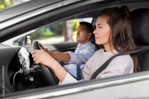 driver courses and people concept - car driving school instructor teaching young woman to drive