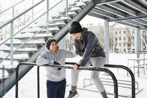 Young sportive couple during calisthenics workout during winter and snowy day