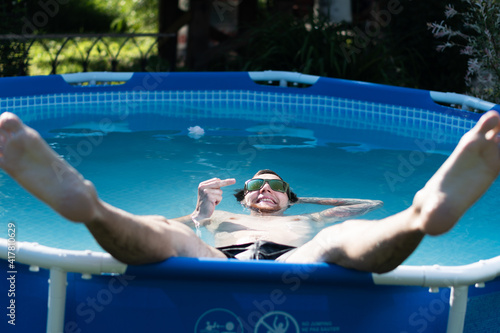 Man in glasses in the summer in a pool showing middle finger, fuck you, provocation and rude attitude.