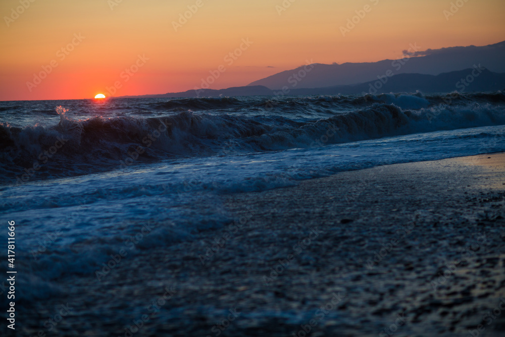 Fototapeta premium beautiful sunset by the sea with strong waves