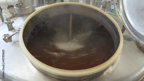 Beer is brewed and fermented in large aluminum tanks. Foam on the surface. Close-up.