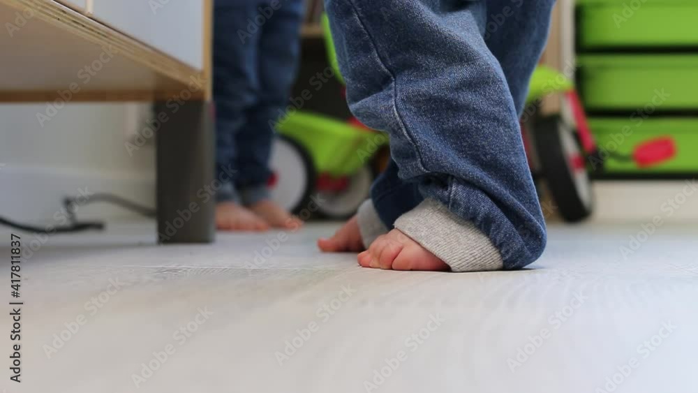 Small children's feet stand on the floor in the children's room. Small children's feet stand on the floor in the children's room.