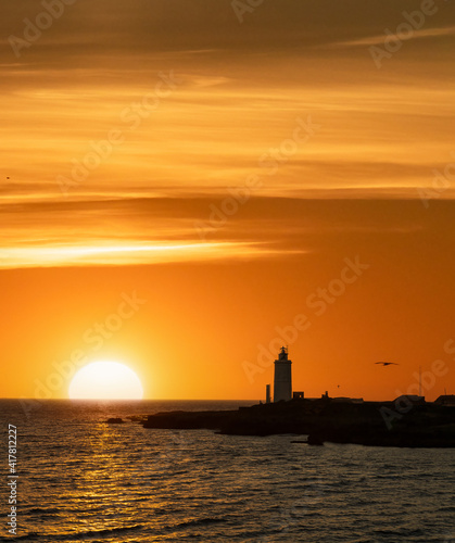 Lighthouse at sunset with sun over the oce