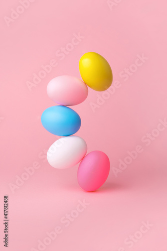 colorful easter eggs balancing over pink background
