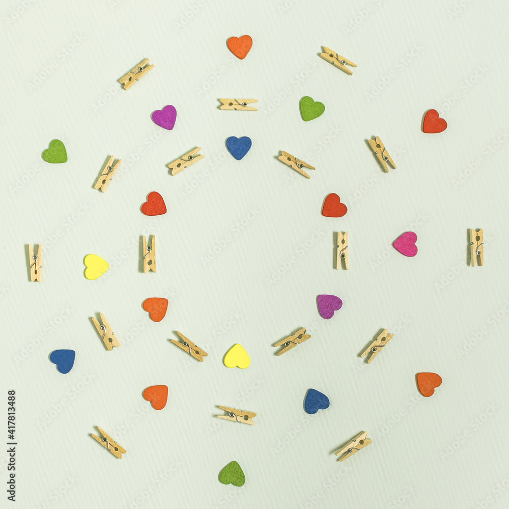 Clothespins and red, blue, green, yellow, purple and orange hearts in concentric circles.Flat lay on white background Clothespins and red, blue, green, yellow, purple and orange hearts in concentric circles.Flat lay on white background