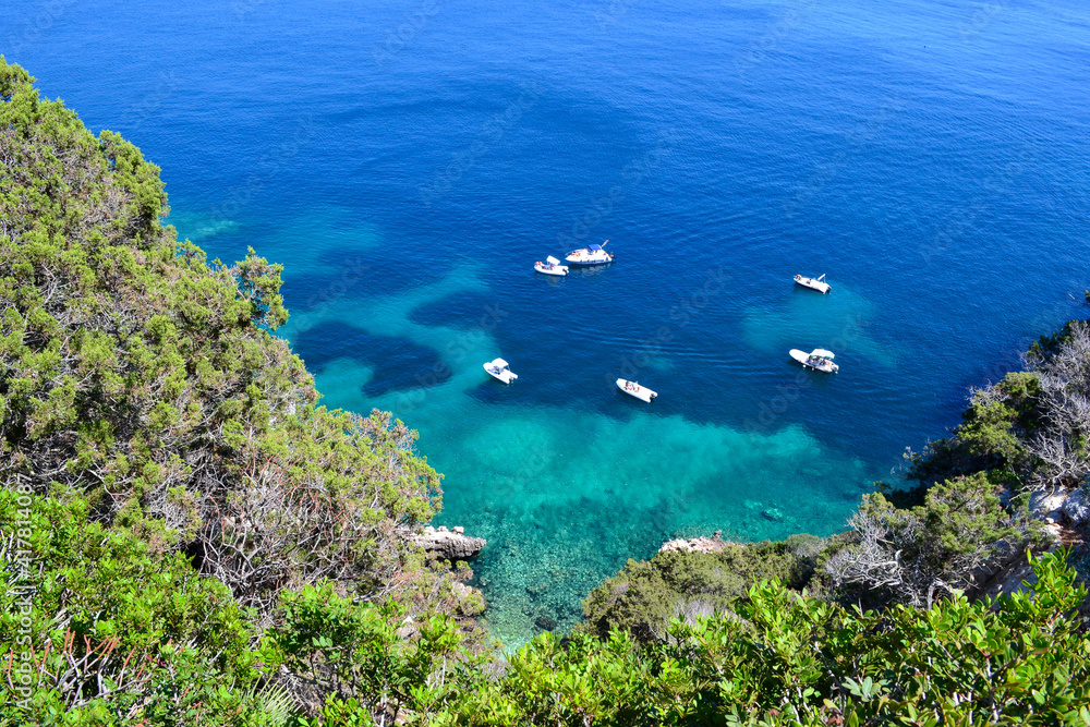 Barche ormeggiate in una bellissima caletta con acqua turchese cristallina - Sardegna (Italia)