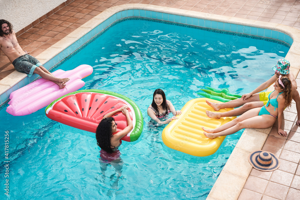 Happy multiracial friends having fun inside swimming pool during summer holidays - Focus on faces Happy multiracial friends having fun inside swimming pool during summer holidays - Focus on faces