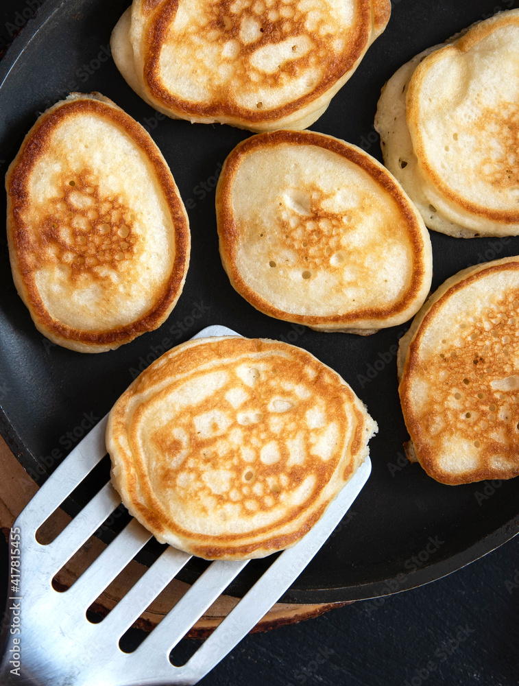 Frying small pancakes in a pan. Close up