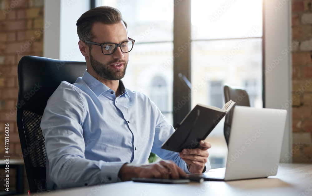 Young entrepreneur checking his schedule at work Young entrepreneur checking his schedule at work