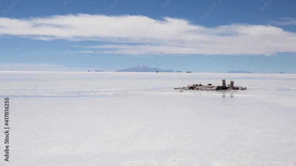 Wide white glittering salty desert of Uyuni, Bolivia. Some salt bricks, little cars and a mountain at great distance. Camera zooms in. Wide white glittering salty desert of Uyuni, Bolivia. Some salt bricks, little cars and a mountain at great distance. Camera zooms in.