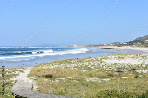 Beach with lighthouse, sand dunes and wild waves breaking at Rias Baixas region. Lariño, Carnota, Coruña, Galicia, Spain.