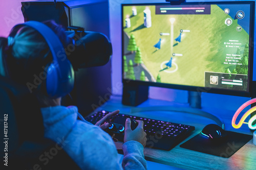 Girl gamer playing strategy game online using virtual reality headset - Focus on right hand photo