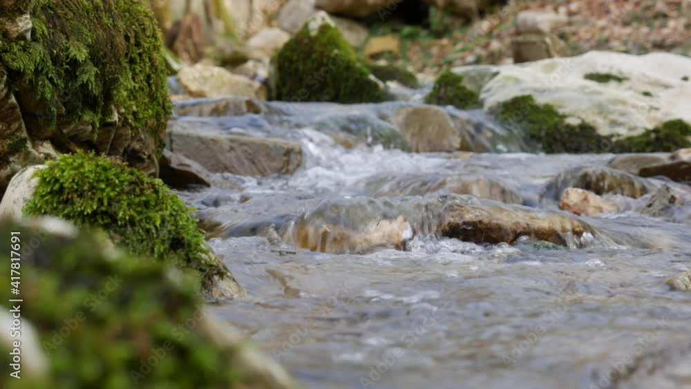Purest mountain creek in the forest. Stream of water moves between the stones covered with moss. Small river with rocks. Idyllic green scenery with small river. Nature background series Purest mountain creek in the forest. Stream of water moves between the stones covered with moss. Small river with rocks. Idyllic green scenery with small river. Nature background series