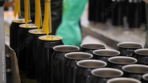 Empty beer cans are filled with fruit beer at the brewery's filling line. Close up.