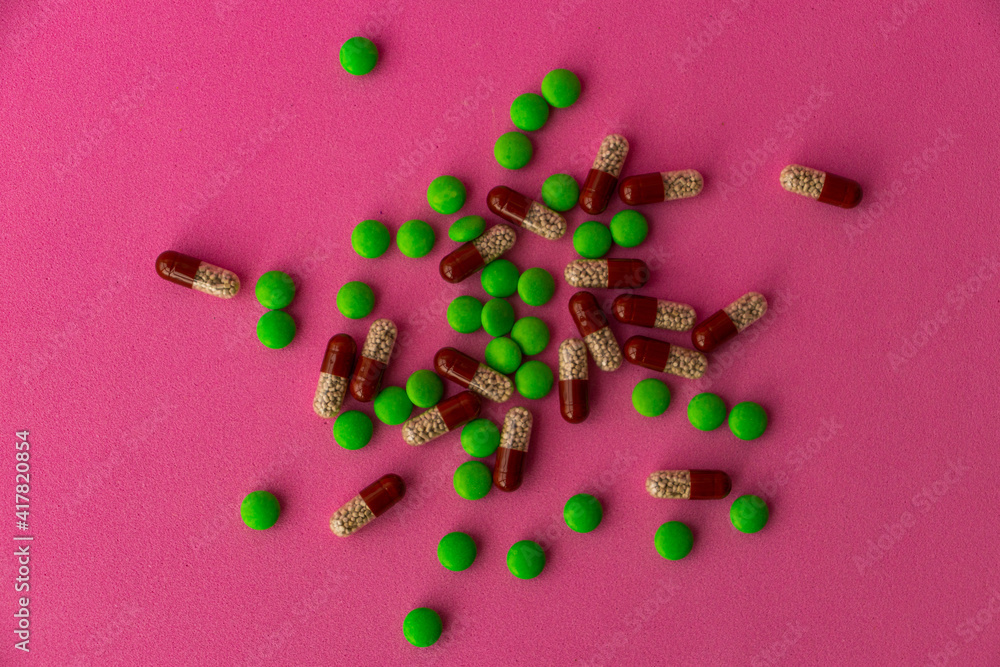 a bunch of different pills vitamins pills and capsules are lying on the table on a pink background close up view from above a bunch of different pills vitamins pills and capsules are lying on the table on a pink background close up view from above