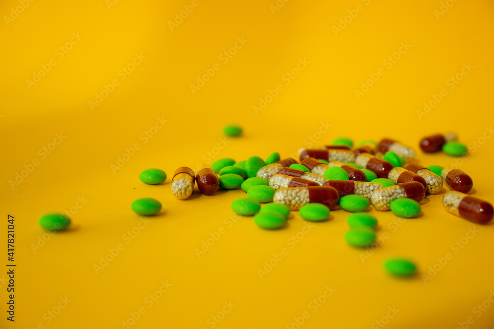 a bunch of different pills vitamins pills and capsules are lying on the table on a yellow background close up view from above a bunch of different pills vitamins pills and capsules are lying on the table on a yellow background close up view from above
