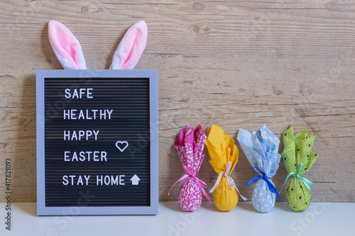 Canvas Print Decorative sign with rabbit ears and colored eggs in side with the easter message: Safe, healthy, happy easter, stay home