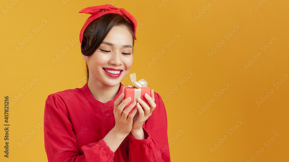 Young woman happy smile hold gift box in hands, isolated over yellow background Young woman happy smile hold gift box in hands, isolated over yellow background