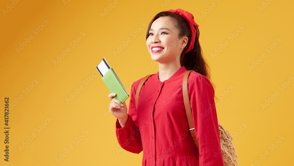 Portrait of a cheerful cute asian girl traveller showing passport with tickets isolated over yellow background Portrait of a cheerful cute asian girl traveller showing passport with tickets isolated over yellow background
