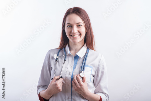 Portrait of a young female doctor in a white uniform in the studio on a white background