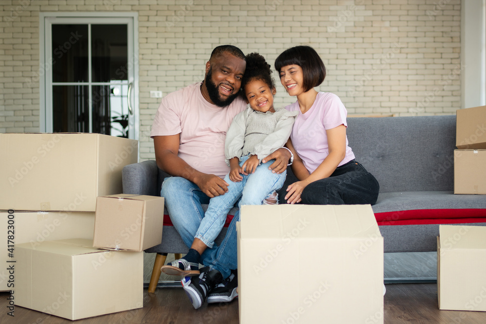 Mixed Race families are sitting on the sofa for rest after moving to a new house on the first day after buying real estate. Concept of starting a new life for a new family. Mixed Race families are sitting on the sofa for rest after moving to a new house on the first day after buying real estate. Concept of starting a new life for a new family.