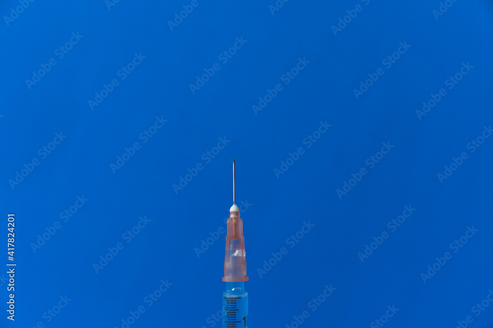 The needle of a syringe with a vaccine close-up on a blue background The needle of a syringe with a vaccine close-up on a blue background
