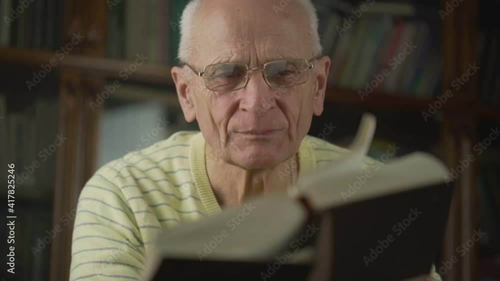 Serious intellectual senior man in eyeglasses reads big book. Concept learning and studying. Serious intellectual senior man in eyeglasses reads big book. Concept learning and studying.