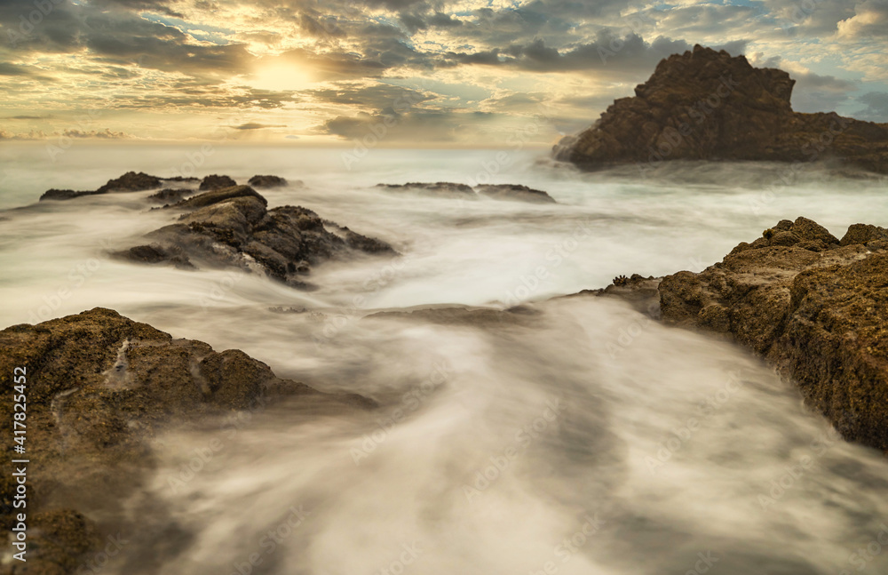 Long exposure water, beautiful seascape, ocean views, rocky coastline, sunlight on the horizon. Composition of nature. Sunset scenery background. Cloudy sky. 