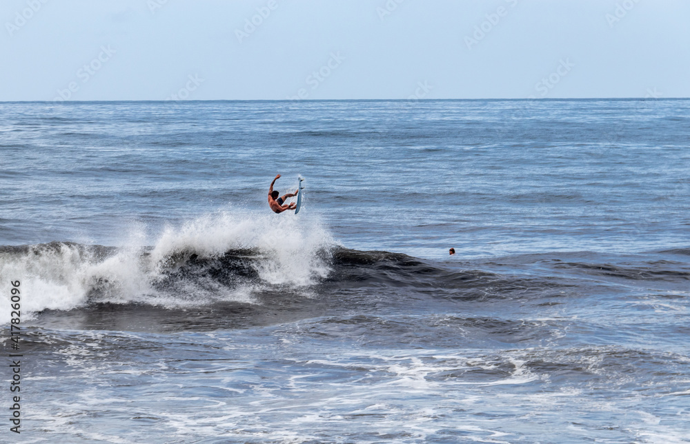 Surfeur en saut sur une vague à Tahiti, Polynésie française