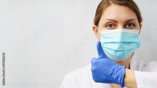 Doctor woman in medical mask shows thumb up.