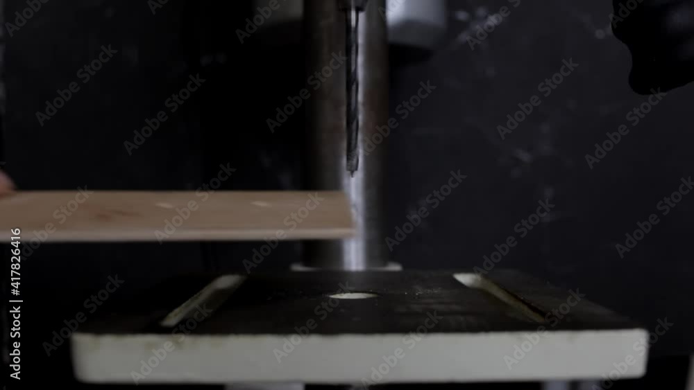 man drills plywood on a bench drill man drills plywood on a bench drill