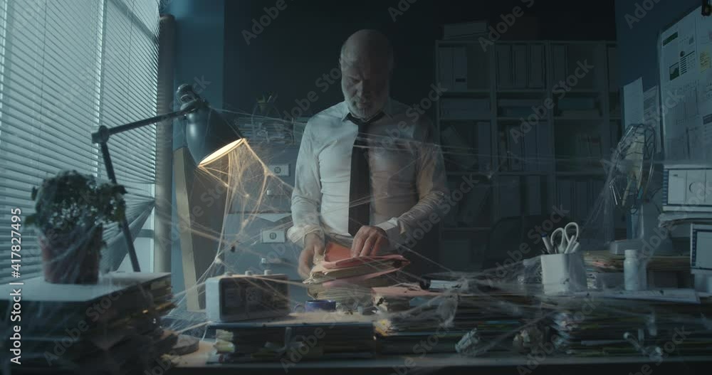 Businessman searching for files in his abandoned office Businessman searching for files in his abandoned office