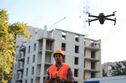 Builder operating drone with remote control at construction site. Aerial photography