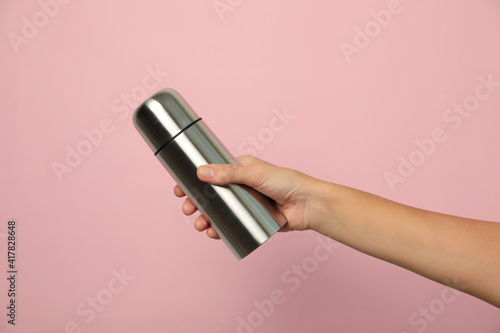 Woman holding modern thermos on pink background, closeup