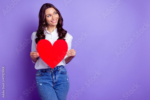 Photo of pretty lady hold heart symbol look empty space wear white shirt isolated violet color background