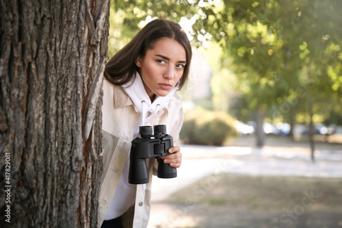 Konstfotografi Jealous woman with binoculars spying on ex boyfriend in park
