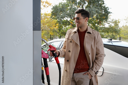 Man taking fuel pump nozzle at self service gas station