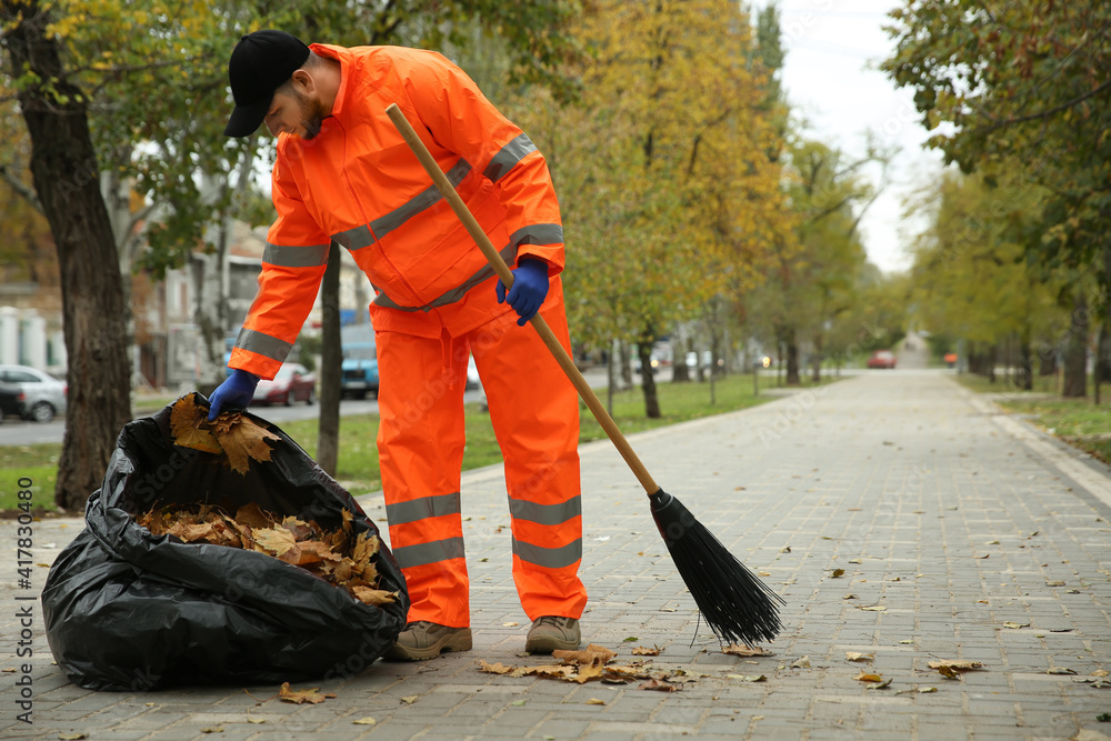 Worker cleaning street from fallen leaves on autumn day Worker cleaning street from fallen leaves on autumn day