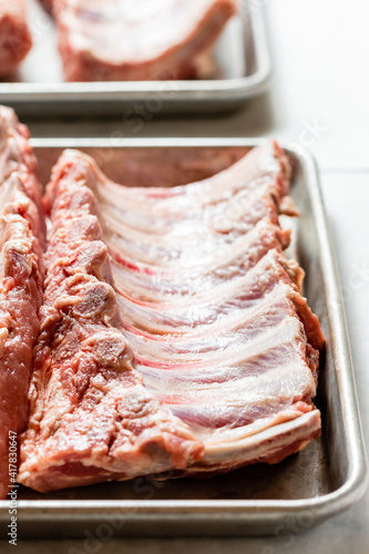 Spare ribs uncooked on stainless steel platter.