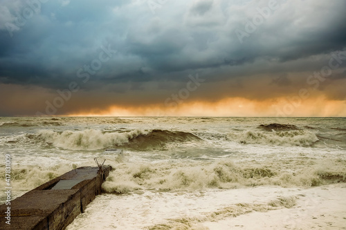 Storm waves near the shore on the beach. In the foreground, breakwaters.