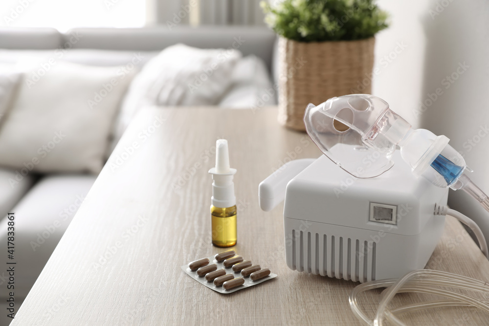 Modern nebulizer with face mask and medications on wooden table indoors. Inhalation equipment Modern nebulizer with face mask and medications on wooden table indoors. Inhalation equipment