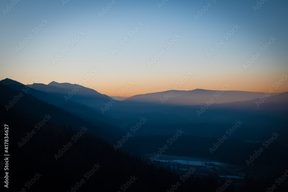 Vibrant colored sunset over Podhale region, Poland. The picture was taken in the way to Nosal Peak, Tatra Mountains. Selective focus on the ridge of the hills, blurred background.