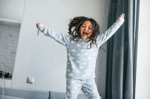 Fototapeta Naklejka Na Ścianę i Meble -  Happy young little girl have fun by jumping on the bed at home