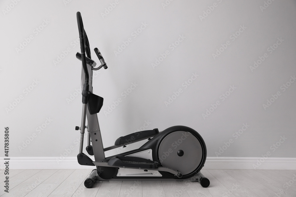Elliptical machine cross trainer near light grey wall indoors Elliptical machine cross trainer near light grey wall indoors