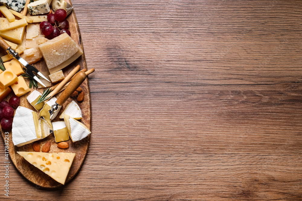 Cheese plate with rosemary, grapes and nuts on wooden table, top view. Space for text Cheese plate with rosemary, grapes and nuts on wooden table, top view. Space for text