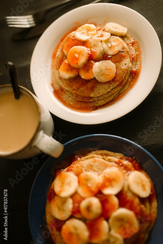 gluten free homemade pancakes with strawberry marmalade and sliced banana closeup photo with hot coffee and dark background