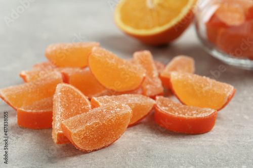 Tasty orange jelly candies on grey table, closeup