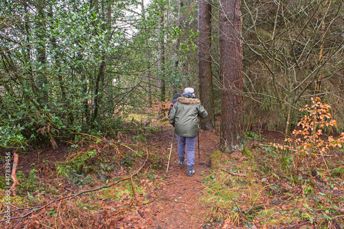 Couple walking on footpath through rural countryside woodland